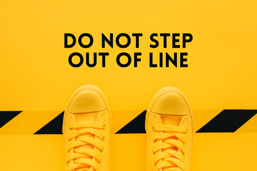 sign saying do not step out of line and feet that are stepping over the line
