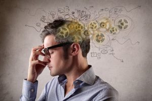 A man thinking with cogs and diagrams around his head