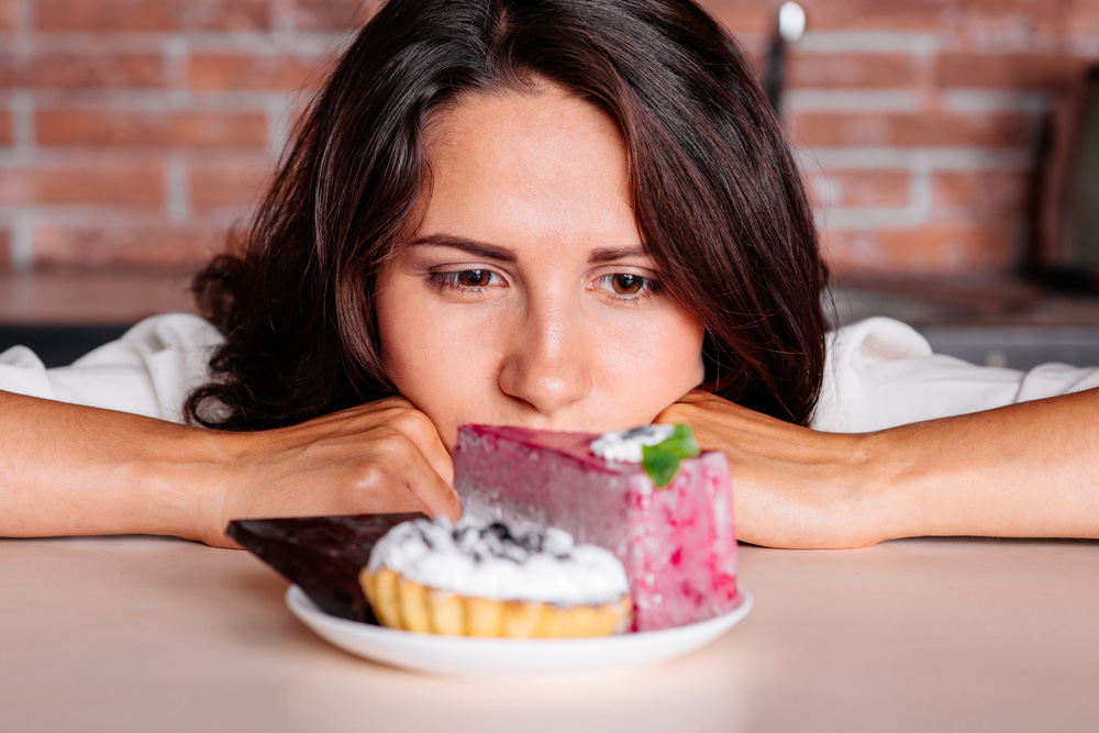 A woman staring at and trying to resist a plate of cakes