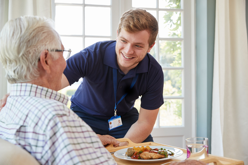 A carer serving dinner and checking on an elderly patient